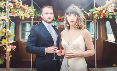 Elegant couple in wedding attire celebrating with champagne and strawberries on a decorated boat.