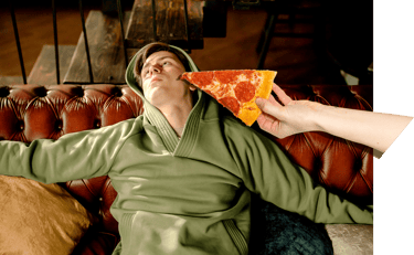 Verveelde jonge man op bank krijgt pizza aangereikt