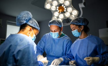 Three surgeons in blue scrubs and masks are focused on  operation in operating room.