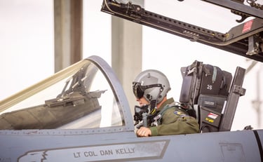 a man in a pilot's helmet sitting in an f-16 fighter jet