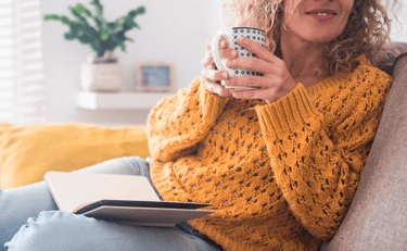 a woman sitting on a couch holding a coffee cup