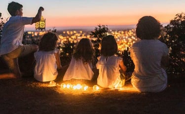 a family sitting on a hill overlooking a city at night