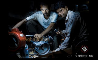 Two mechanics, one in Suzuki T-shirt, repairing an engine with a wrench in a workshop.