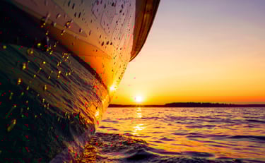 Beautiful picture of a boat hull at the waterline reflecting the gorgeous sunset.