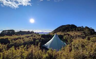 a tent pitched up in the grass near a mountain in Taiwan