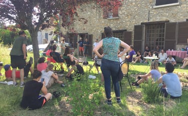 a woman standing in a garden with people sitting around