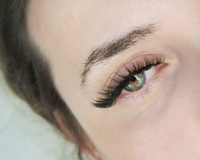 Femme recevant un service de pose de cils avec une Technicienne d'extension de cils