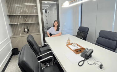 a woman sitting at a table with a phone in front of her