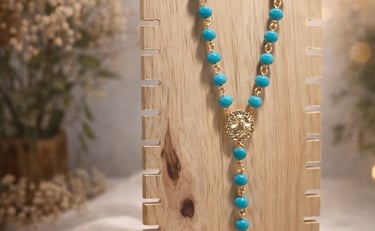 Set de rosario con pulsera y aretes color azul en un fondo de flores y madera