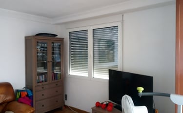 Ventana de dos hojas con persiana en estancia.