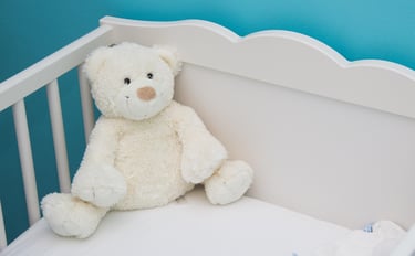 Newborn sleeping comfortably in swaddle blanket inside crib.