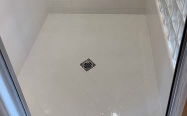 After photo of professional shower restoration with clean white tile walls and floor.