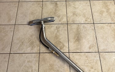 Tile floor being professionally cleaned with wand, showing visible difference between dirty and clea