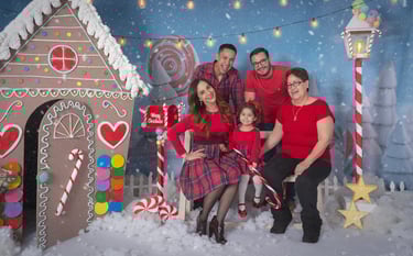 a family posing for a photo in front of a gingerbread house