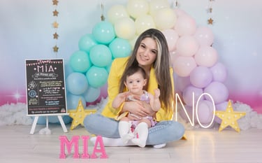 a woman holding a baby in front of a rainbow colored backdrop