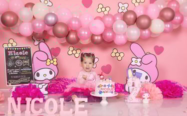 a baby girl in a pink dress and pink balloons