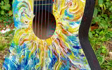 peinture sur guitare aux couleurs vives, avec un soleil autour de la rosace et des formes abstraites