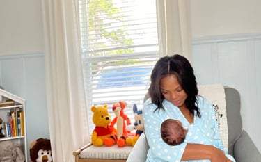 a woman in a blue polka dotty dress is holding a baby