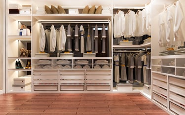 Organized walk-in closet with hanging clothes and storage by KLEAN WELL