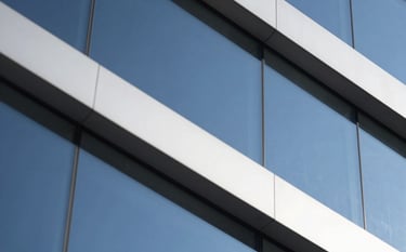 Abstract close-up of geometric architectural shapes and glass panels reflecting a deep blue sky. Sharp edges, clear lines, and a sense of orderly structure. High-end and technical feel. Colors used: #2D5D6D, #F5F5F5, #1A1A1A.