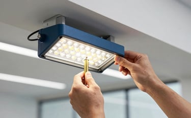 A close-up of a skilled technician installing commercial LED fixtures in a sleek North American / US office space. The image focuses on efficiency and precision, featuring accents of Steel Blue and Muted Gold in the equipment and Soft White architectural lighting.
