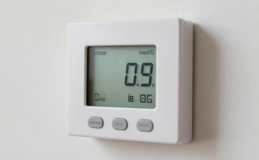 Close-up of a high-efficiency thermostat on a clean wall, showing a comfortable temperature setting. The lighting is soft and professional, emphasizing comfort and control.