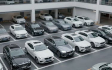 A high-angle view of an impeccably organized parking facility with luxury vehicles perfectly aligned. The environment is clean, professional, and features modern lighting and dark flooring, reflecting the #1A1A1A palette.