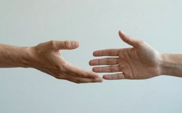 Two hands reaching out toward each other in a gesture of support and connection, set against a soft, textured background in shades of #AABCCB and #F8FBFD. The lighting is warm and comforting, suggesting empathy and professional psychological guidance.