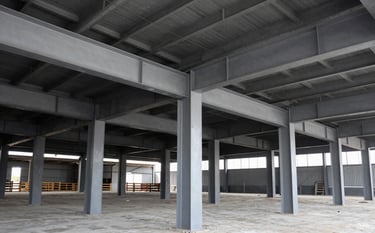 Massive structural steel beams and columns for an industrial warehouse under construction in Guadalajara, North American / Mexican setting, high-angle view, minimalist industrial style, Silver Gray and Carbon Black tones, bright daylight, professional architectural photography.