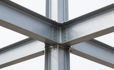Close-up of a high-complexity structural joint in a modern steel building, visible precision welding and heavy bolts, industrial minimalist aesthetic, Silver Gray steel against a White backdrop, North American / Mexican construction site, sharp clean lines.