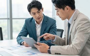 Two business professionals in North American / US business-casual attire reviewing a structured financial plan on a tablet in a brightly lit, modern conference room. The atmosphere is collaborative and forward-thinking. Colors include medium teal and off-white.