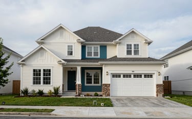 Clean architectural photography of a well-maintained North American residential property. The shot is wide-angle, showing the front facade and a neat driveway under a soft, overcast sky. The house colors are off-white and deep teal.