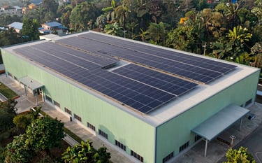 A professional architectural photograph of a large commercial facility in Dehradun with a massive solar panel array on its flat roof. The composition is modern and industrial, utilizing forest green accents and clear morning lighting to convey efficiency and reliability.
