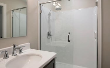 A pristine bathroom in a US suburban home, featuring white porcelain, polished chrome fixtures, and a glass shower door with no water spots, emphasizing professional attention to detail.