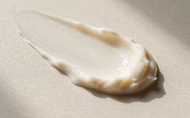 A professional macro photograph of a thick ivory skincare cream texture with soft ridges, lit by soft morning light in a minimalist North American / US luxury dermatology setting, ivory and soft beige tones.