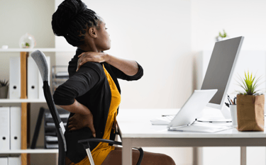A black lady experiencing back pain due to poor Ergonomics