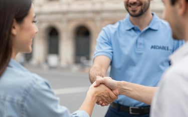 A close-up of a professional technician in a branded uniform shaking hands with a relieved customer in Rome. Trustworthy, clean, and modern atmosphere using palette colors #8DAFB5 and #1A2E35.