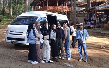 Dua orang pria enam orang perempuan berpose di depan Hiace putih dengan pintu terbuka.