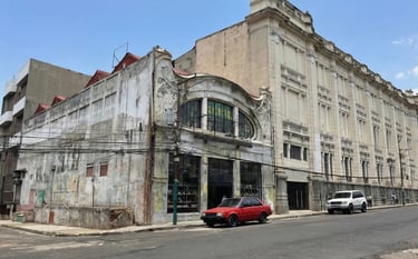 Historic art deco architecture in San Salvador featuring a red car parked on a city street.