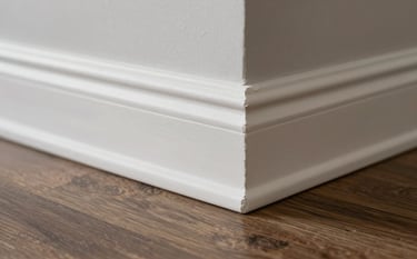 A detailed macro photograph showing a pristine white baseboard installed against a deep warm brown-grey laminate floor in a sophisticated South American / Brazilian residence. The lighting is soft, highlighting the professional finishing and seamless joints.