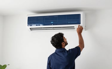 A high-end split air conditioner being installed by a specialist on a minimalist white wall in a South Asian / Indian living room. The lighting is clean and professional, emphasizing a modern lifestyle and trust. The palette includes Dark Navy and Steel Blue tones.