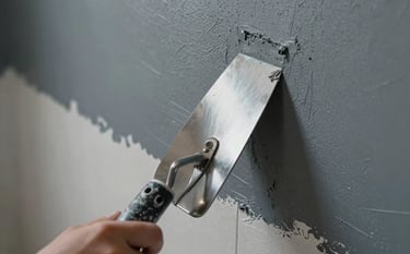 Close-up of a modern wall finishing process in a Brazilian residence. A stainless steel trowel is applying a smooth layer of gray plaster. The composition is clean and technical, emphasizing precision and the high-quality finish typical of professional masonry work. Palette of dark blue-gray and light gray.