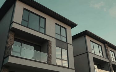 A low-angle shot of a modern North American / US residential development with clean lines, glass windows reflecting a deep sage green sky at dusk.