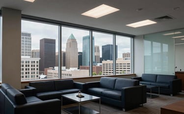Interior of a modern, upscale financial office in Spokane, Washington. A large window overlooks a professional North American city skyline during the daytime. The room is filled with dark navy furniture and light blue glass accents. The atmosphere is quiet, professional, and sophisticated.