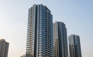 A high-angle architectural photograph of a luxury high-rise residential building in a major North American city, emphasizing glass facades and modern engineering, captured in bright daylight with a clear off-white and blue sky.