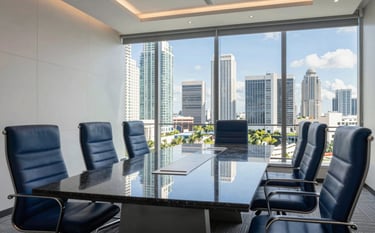 A sleek, modern high-rise boardroom in Miami overlooking a sunny skyline. The room features a polished dark obsidian table and gunmetal blue designer chairs. The lighting is bright and natural, reflecting a clean, professional investment environment.