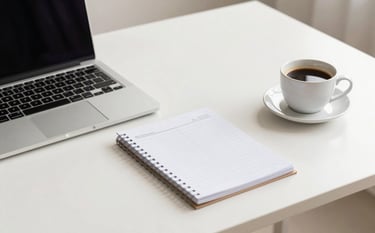 A minimalist and bright home office desk featuring a sleek laptop, a clean paper planner, and a cup of coffee. The color palette includes soft off-white surfaces and warm taupe accents, creating an atmosphere of focus and professional clarity.