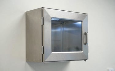 A stainless steel dynamic pass box integrated into a sterile laboratory wall in a South Asian / Indian research center. The design is modern and minimalist. Clean lighting reflecting off steel surfaces. Off-white and Steel Blue palette.