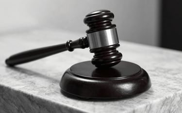 A powerful black and white close-up of a wooden gavel on a silver grey marble pedestal. The lighting is dramatic, creating deep black shadows and sharp white highlights, emphasizing authority and justice.