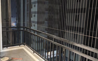 A luxury apartment balcony featuring modern invisible grills made of thin stainless steel cables. Th